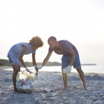 Two people collecting trash on beach