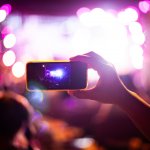 People taking photographs with smart phone during Live music concert and crowd in background