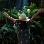 Cute Asian Little Girl Playing In The Rain Forest, The Morning’s Interesting Sun Shines Through The Trees