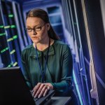 Female IT engineer typing code in the server room