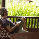 Man holds digital tablet, looks out to jungle