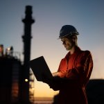 Asian man engineer using digital tablet working late night shift at petroleum oil refinery