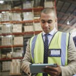 Manager using digital tablet in distribution warehouse