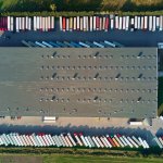 Factory warehouse with parked semi trucks, aerial view