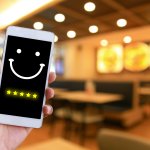 Woman is pressing face emoticon on virtual touch screen at smartphone.