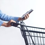 Closeup of woman with shopping cart and shopping list in smartph
